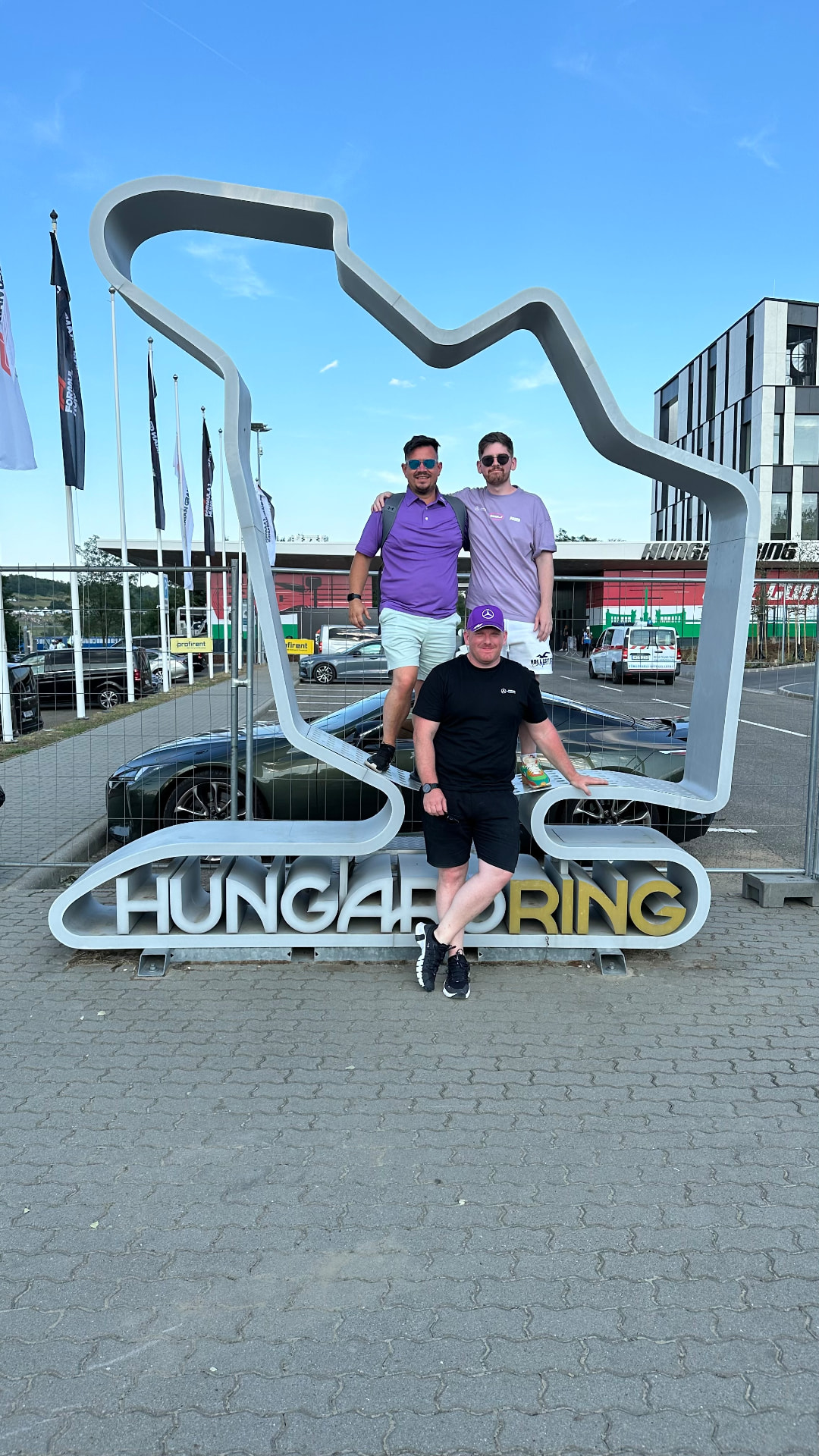 Jon and two friends posing on the Hungaroring Formula 1 circuit track outline