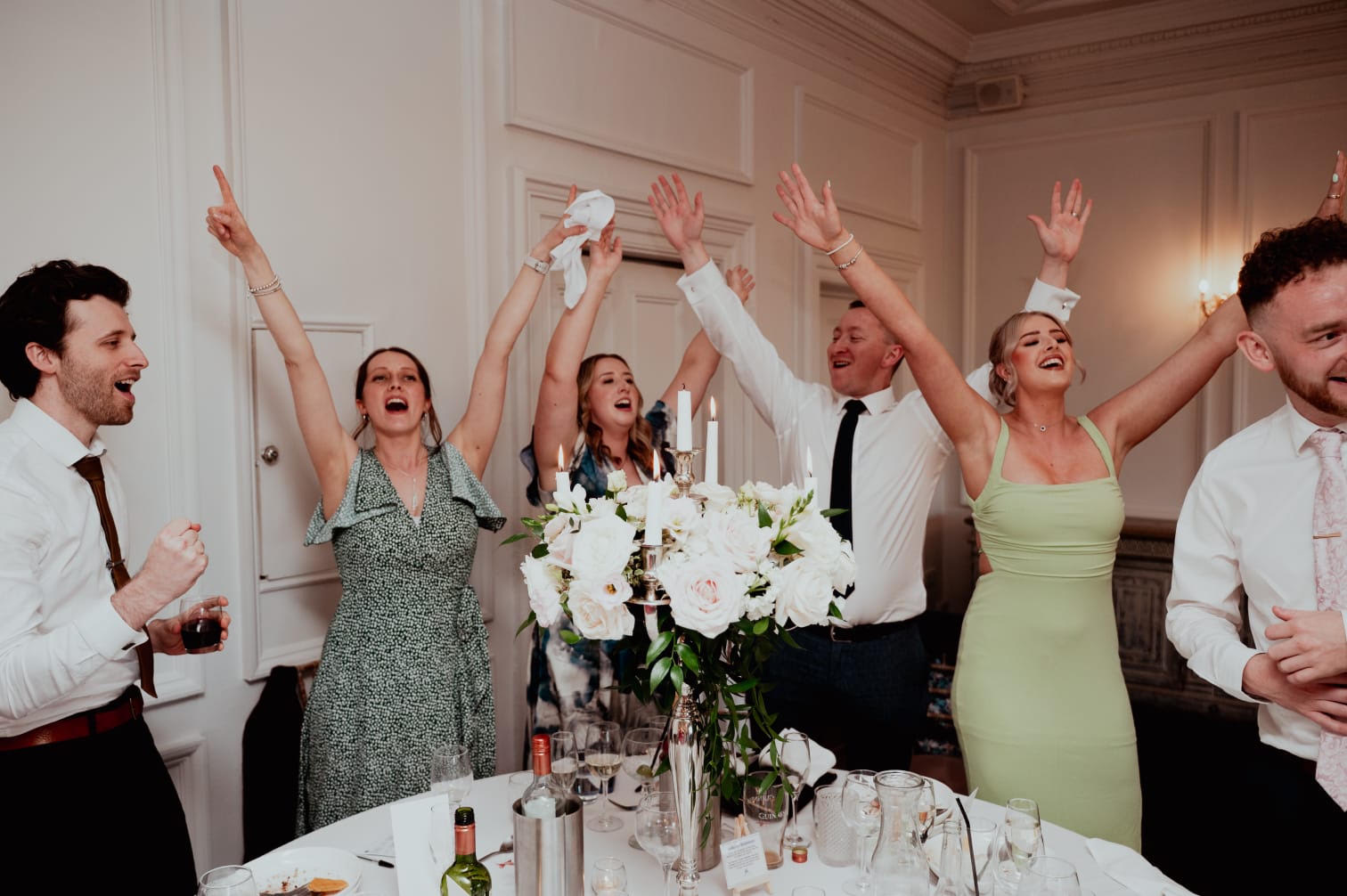 Wedding guests cheering with their arms raised