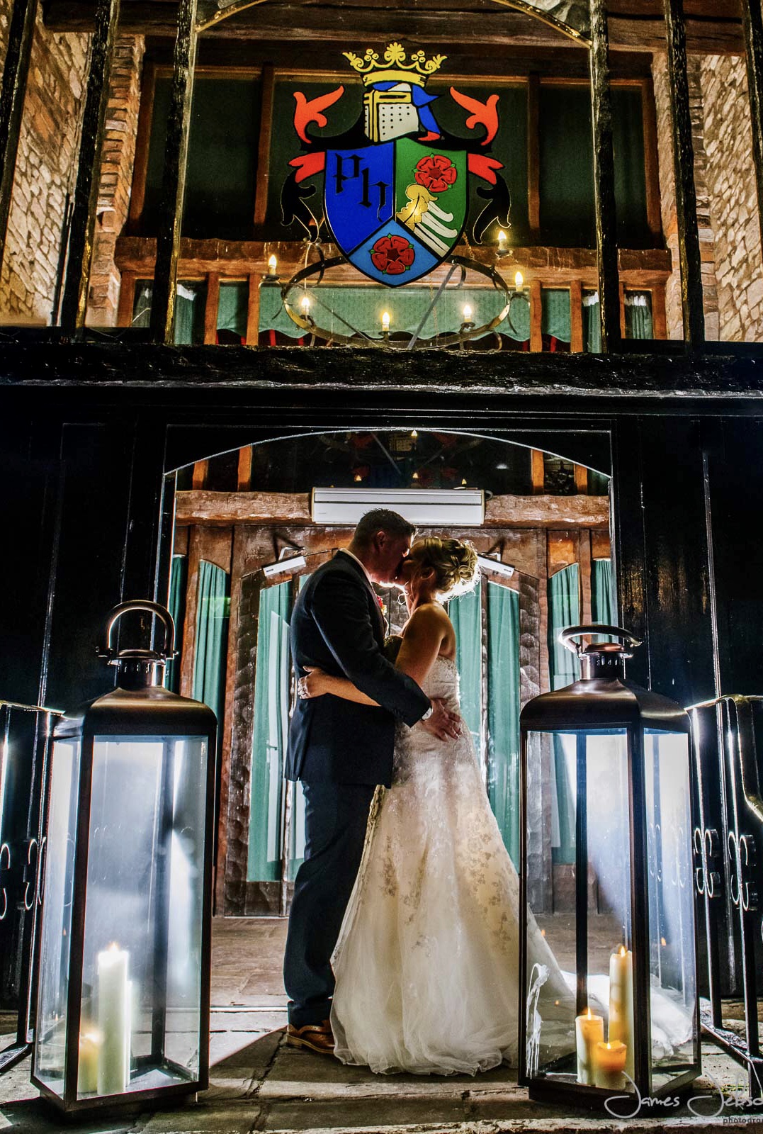Jon and Mel kissing on their wedding day in a torchlit venue entrance