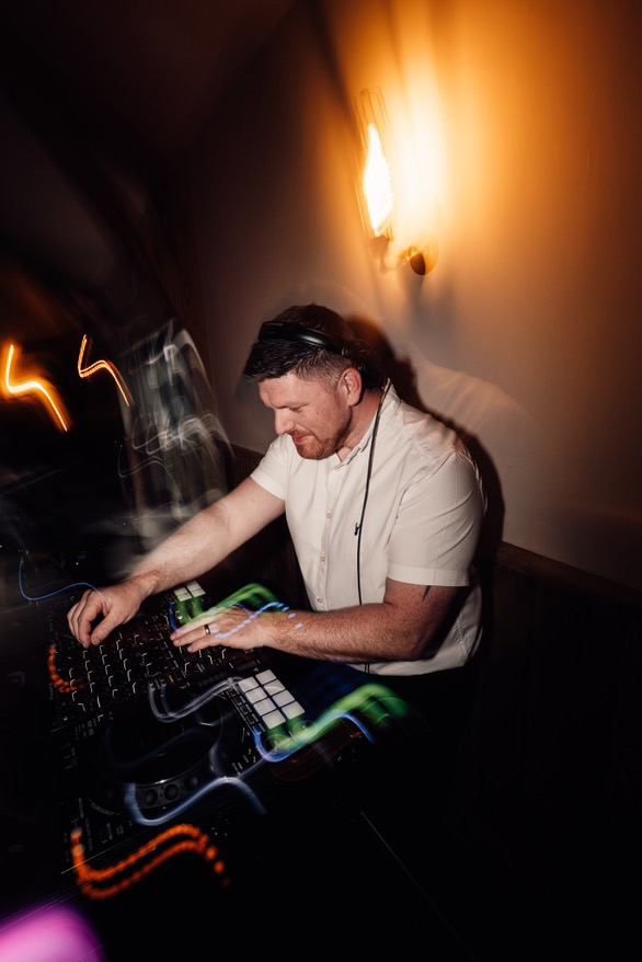 Jon mixing at a DJ controller with light trails