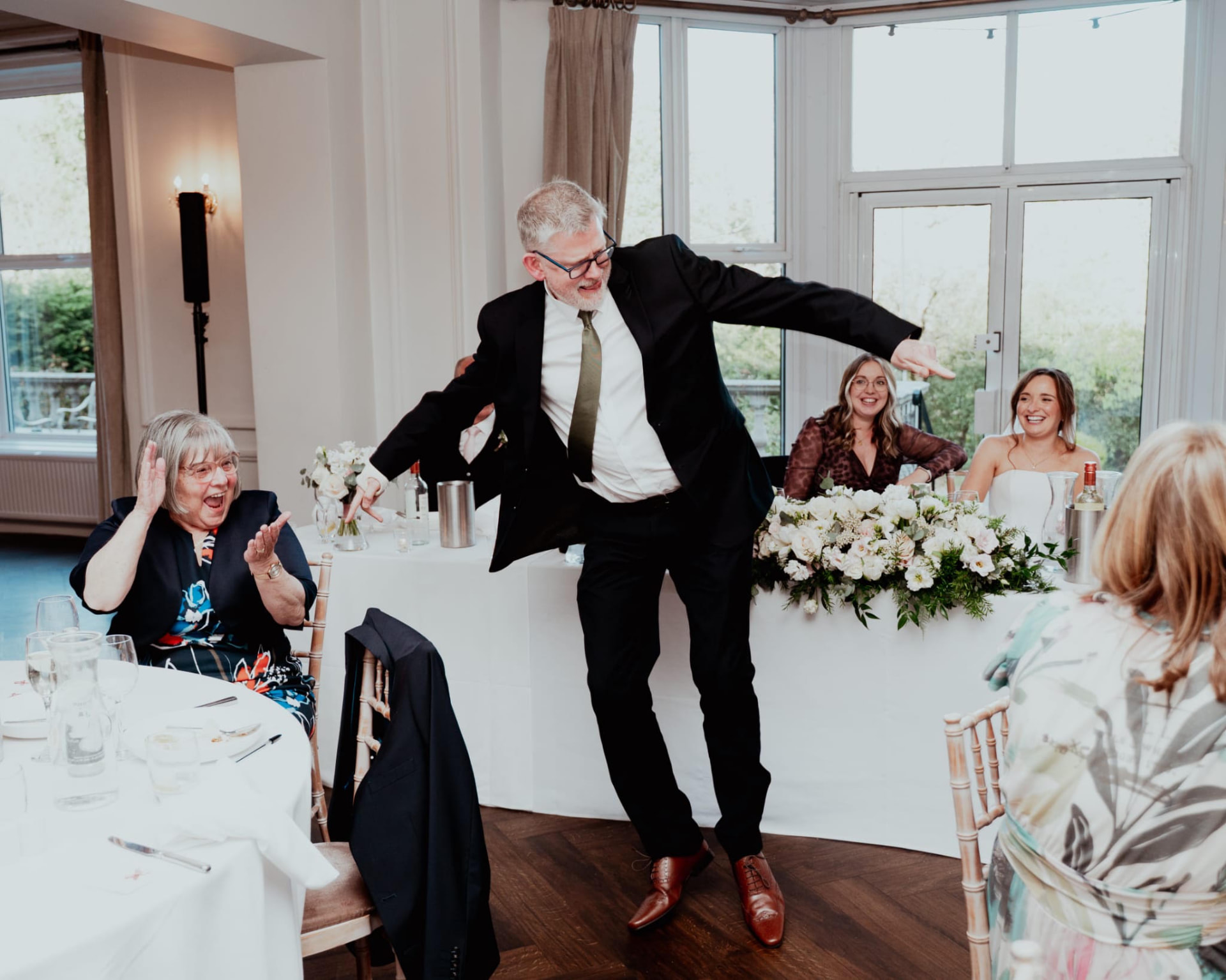 Jon dancing at a wedding breakfast as guests watch