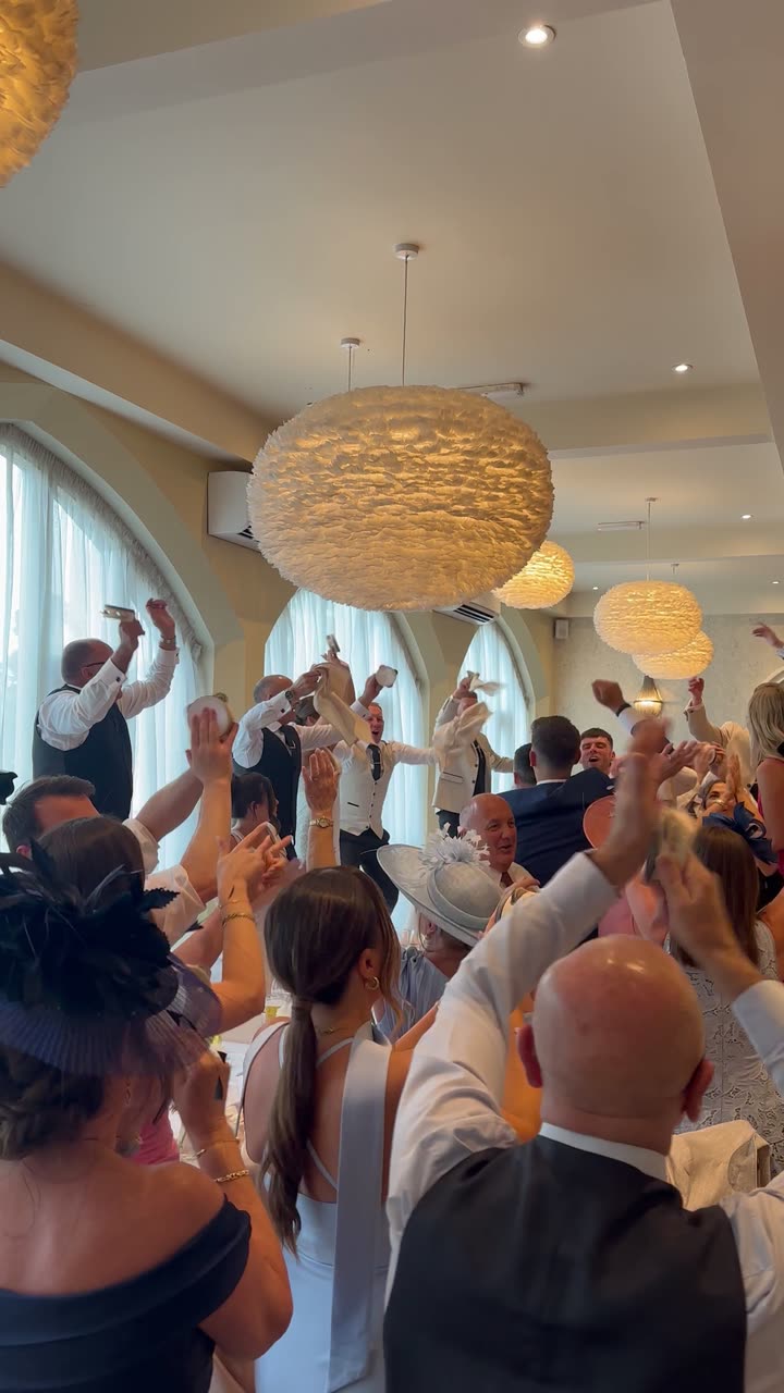 Guests waving napkins and tambourines during the wedding breakfast