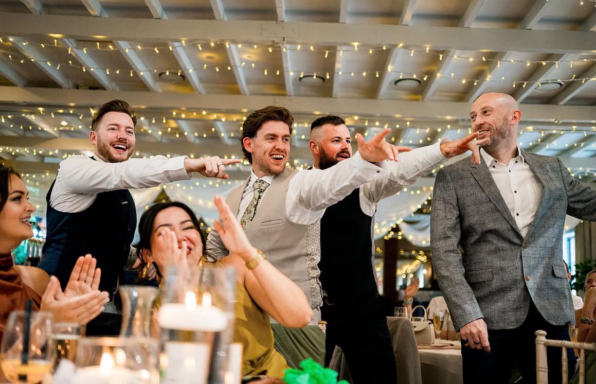 Wedding guests laughing and cheering around a table