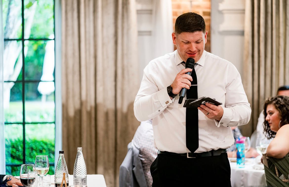 Jon speaking into a microphone at a wedding