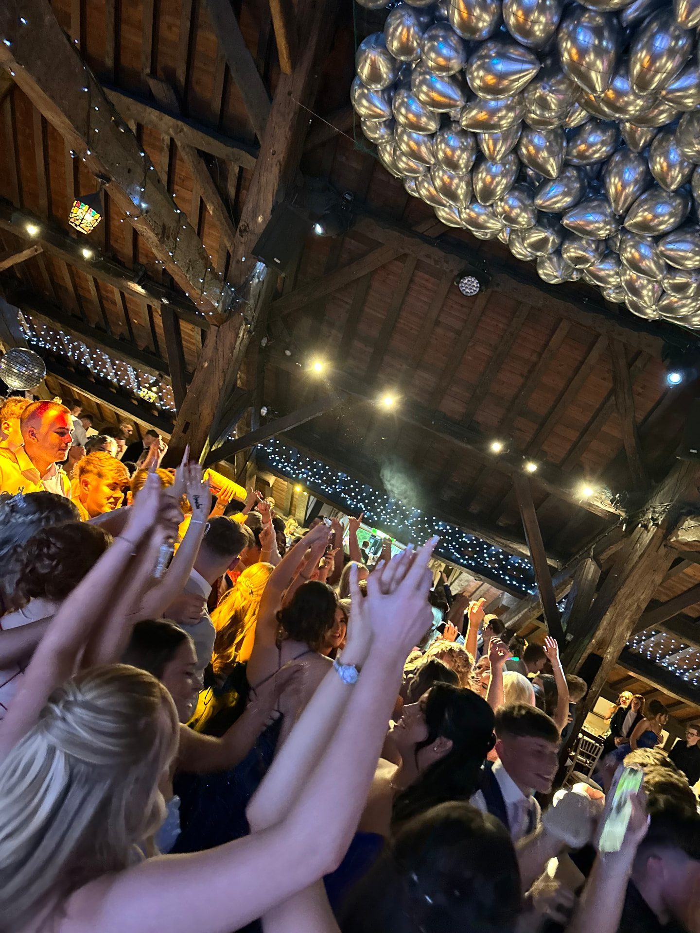 Guests dancing with arms raised under warm lights