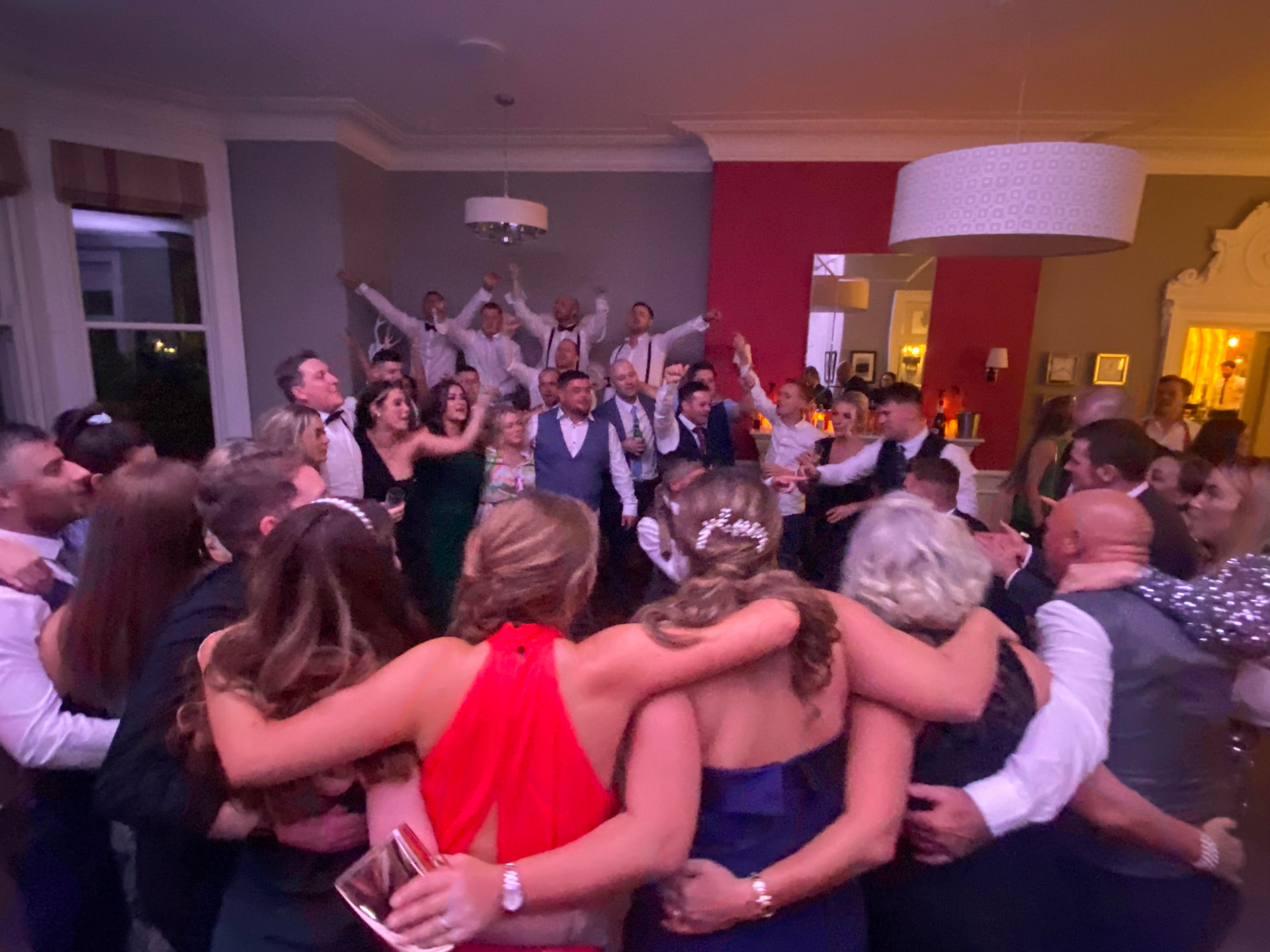 A party crowd with arms linked, singing together